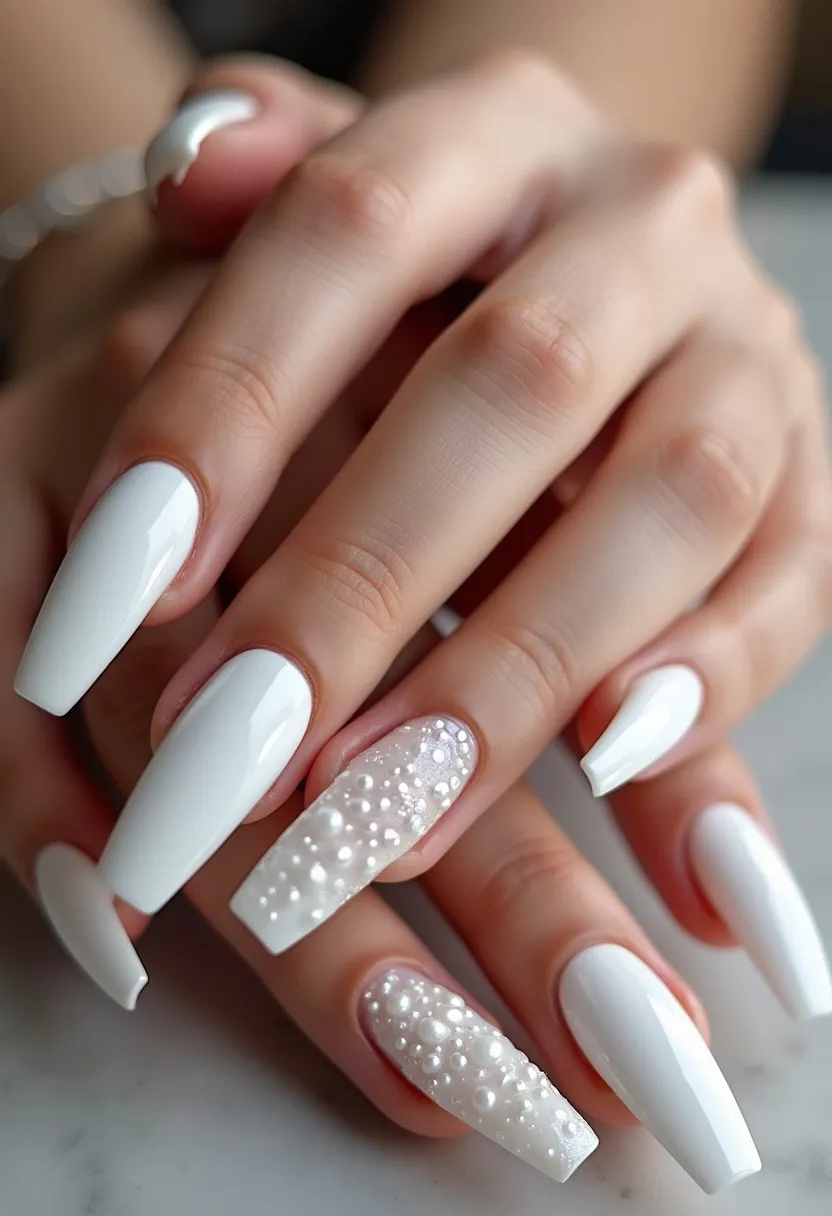 The nail design features a refined and elegant palette primarily consisting of a pristine white color. The nails are of a long, coffin shape, which adds a touch of sophistication to the overall look. The design incorporates intricate patterns and decorations, specifically on the ring finger of each hand, adorned with detailed pearl-like embellishments creating a textured and luxurious effect. This particular treatment seems to be a gel manicure, given the high gloss and smooth finish observable on the surface. The unique details of the beadwork on the accent nails provide a 3D effect, making the design stand out. This design is perfect for special occasions, notably weddings or formal events, due to its elegant aesthetic and detailed embellishments.