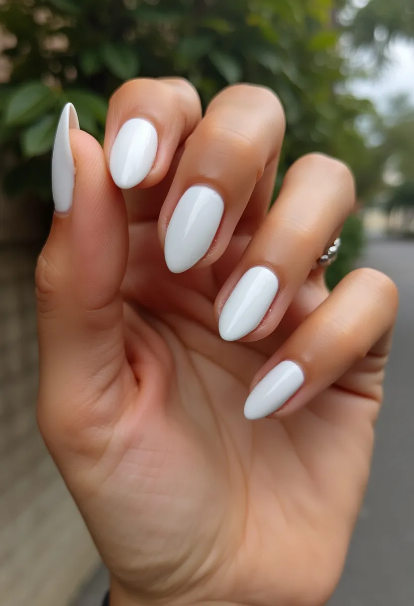 This nail design features a timeless, elegant look with a monochromatic white color palette. The nails are shaped in an almond style, offering a feminine and classy appearance. The white polish has a glossy finish, indicative of a gel nail treatment, which provides a smooth and even surface. There are no intricate patterns or additional decorations on the nails, keeping the design minimalistic and versatile. This clean and fresh look is suitable for various occasions, including weddings, formal events, or as an everyday sophisticated style. The high-gloss finish and pristine color make these nails ideal for any season, though they particularly complement a bridal or summery theme.